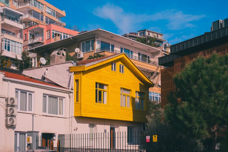 A striking yellow house contrasts with surrounding buildings in Istanbul, Türkiye.