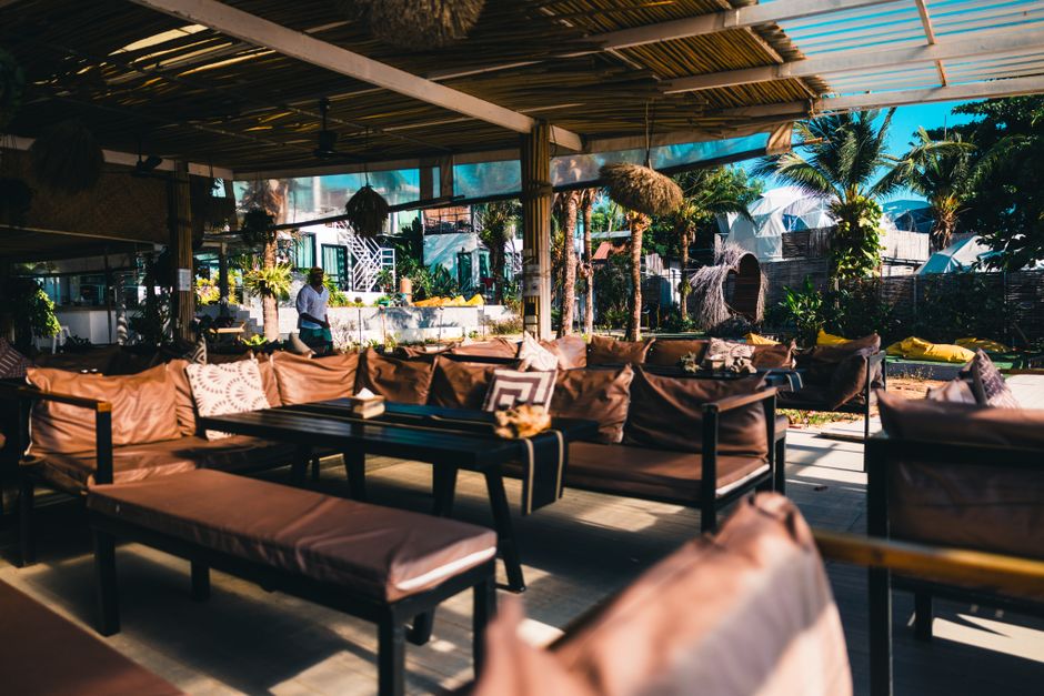 Relaxing outdoor seating area in a tropical restaurant in Phuket, Thailand with lush greenery.