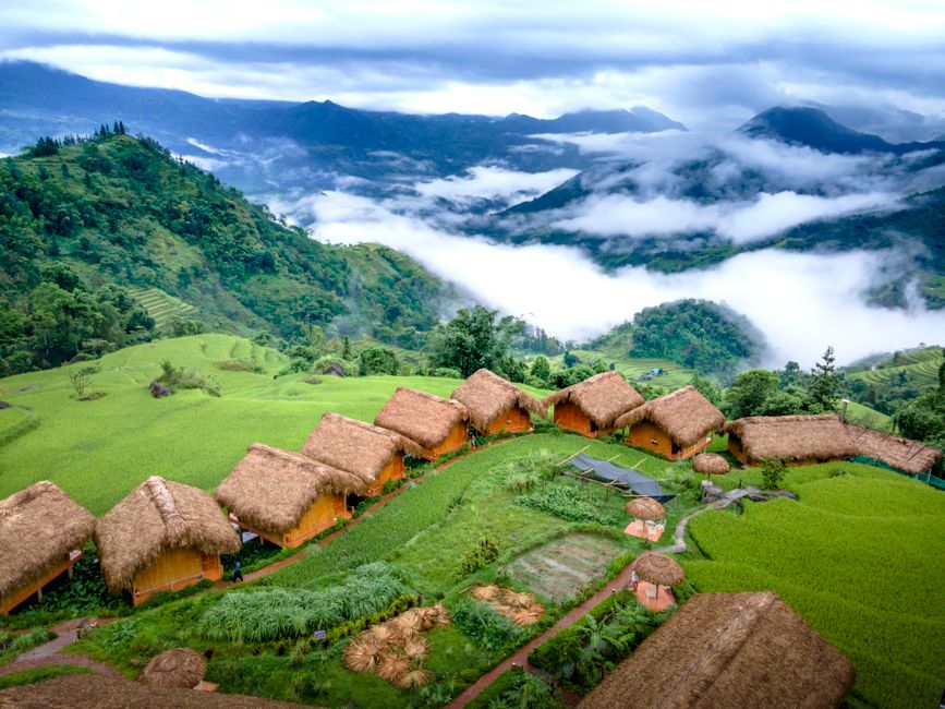 Breathtaking aerial view of a Vietnamese mountain lodge surrounded by lush greenery and foggy peaks.