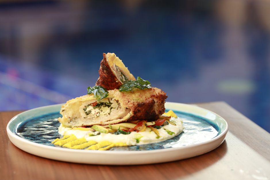 A delicious fried chicken dish with cheese sauce artfully plated on a ceramic plate.