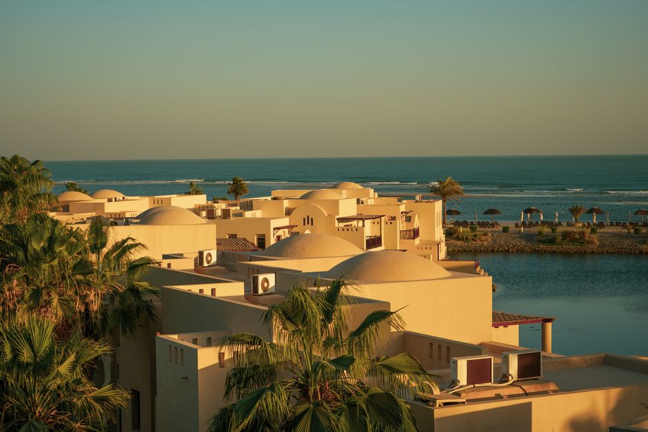 Aerial view of elegant villas with unique architectural style by the seaside during sunset.