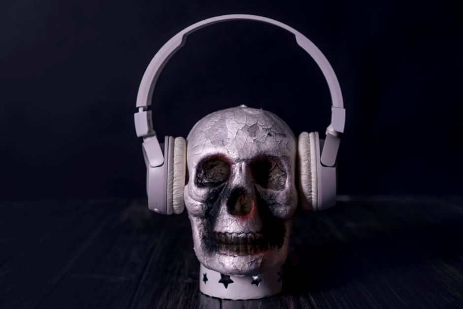 A creepy skull adorned with headphones, casting an eerie vibe against a black background.