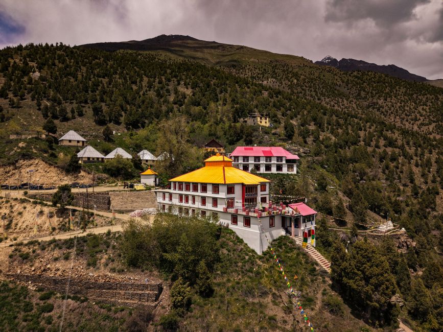 A scenic view of a colorful Buddhist monastery nestled in the lush green hills of the Himalayas.