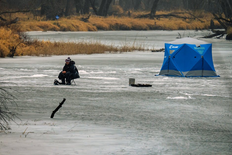 Ice fisherman with tent on a frozen lake, showcasing serene winter landscape.