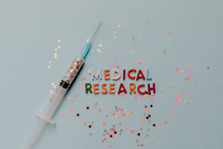 Close-up of a syringe with colorful confetti on medical research theme.