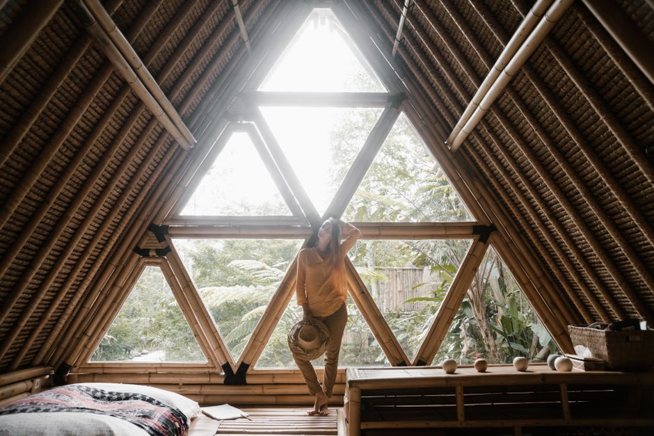 A relaxing person in a bamboo cabin filled with natural light and lush greenery outside.