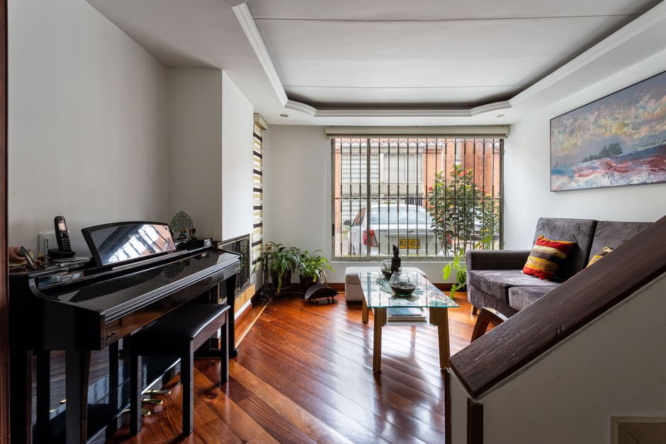 Bright living room featuring a grand piano, wooden floors, and stylish decor.
