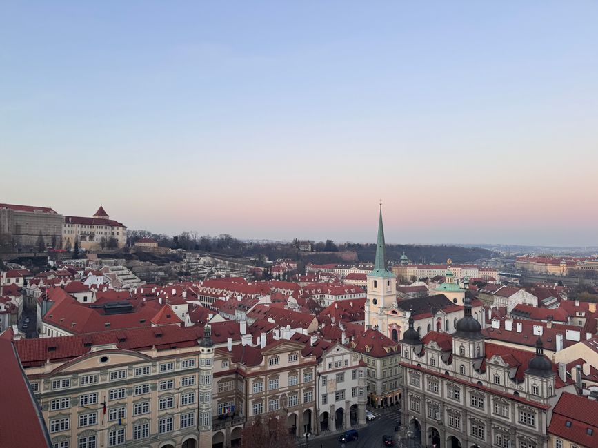 Aerial view of Prague Old Town with red roofs and church spire at twilight, Czech Republic.