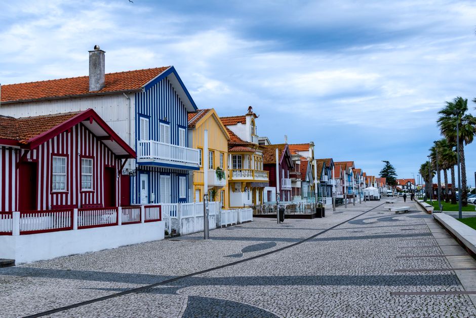Vibrant striped cottages lining a coastal promenade in Costa Nova, Portugal.