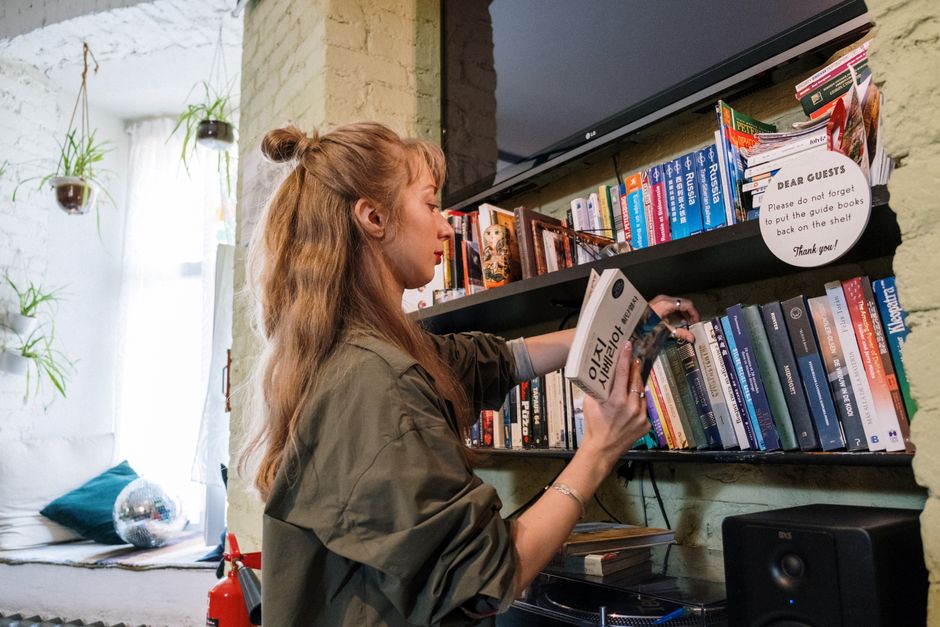 A woman browsing books on a shelf in a cozy indoor setting, capturing a love for literature and education.