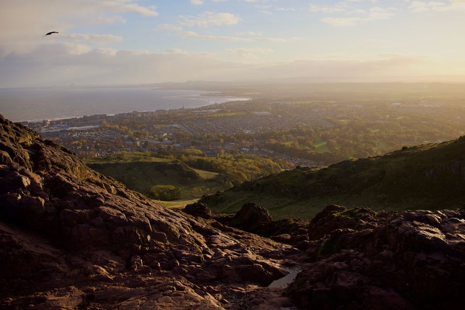 Stunning panoramic view of Edinburgh cityscape from Arthur's Seat during sunset.