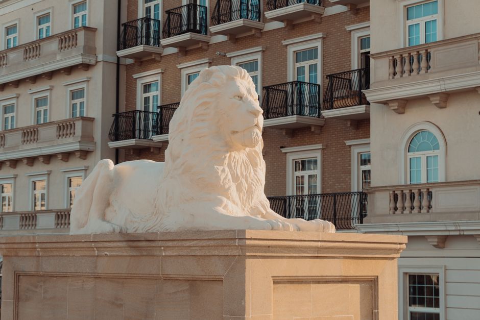 Elegant lion statue against a classic architectural building in Baku, creating a serene urban scene.