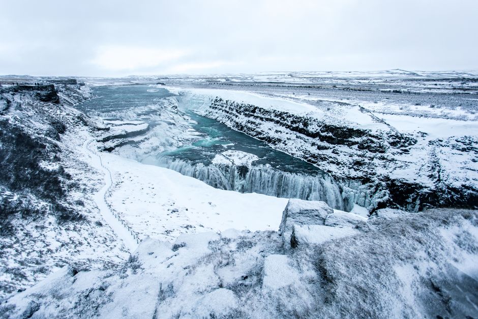 Majestic winter landscape of Gullfoss waterfall surrounded by snowy terrain in Iceland.