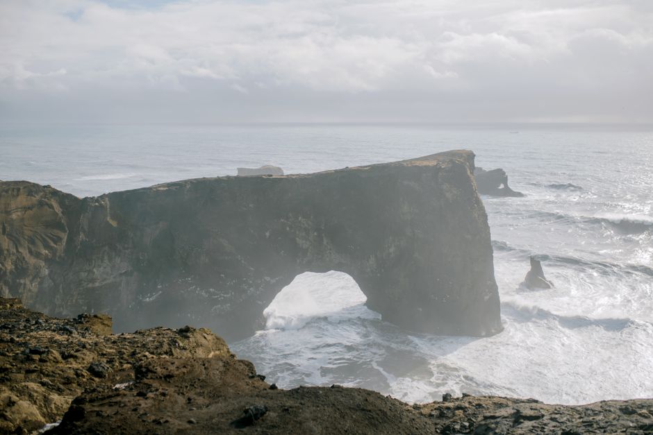 Stunning view of the iconic Dyrhólaey arch with waves crashing below, showcasing Iceland's dramatic landscape.