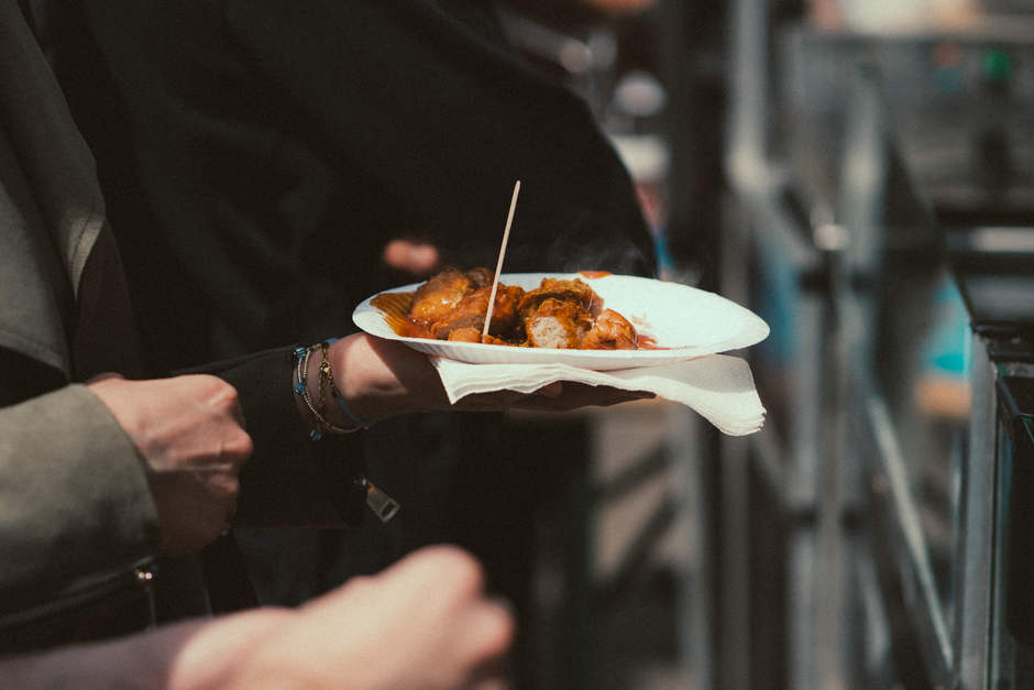 Person holding a plate of savory street food at an outdoor market.