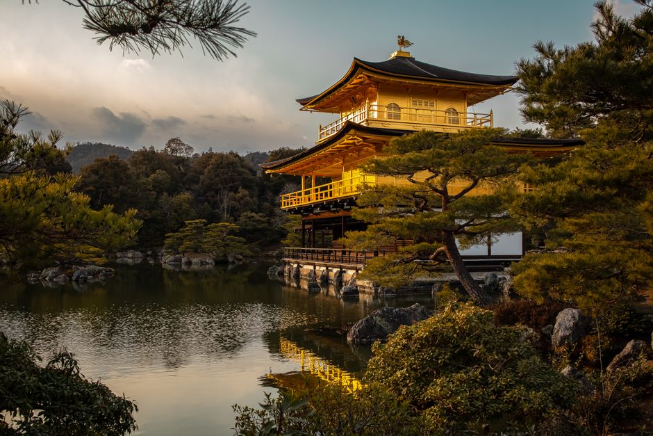 Stunning view of Kinkaku-ji reflected in a serene pond under the warm sunset light.