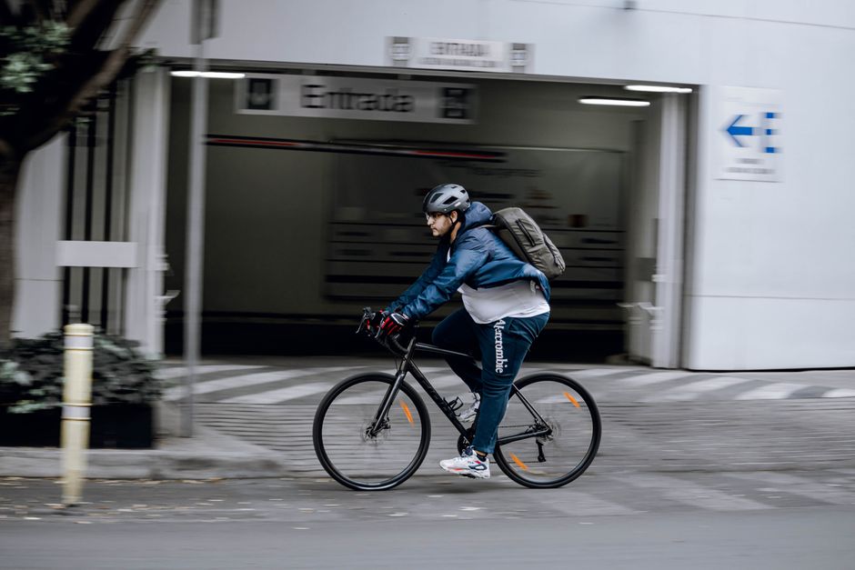 A man rides a bicycle quickly through a modern city street, showcasing urban mobility.