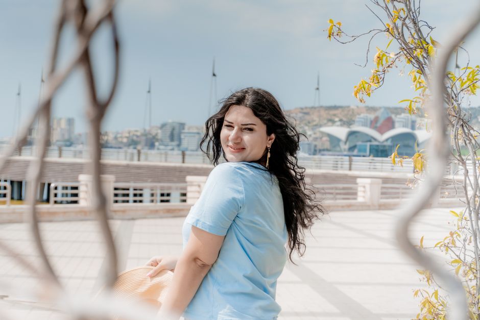 Stylish woman enjoying a sunny day with Baku cityscape in the background.