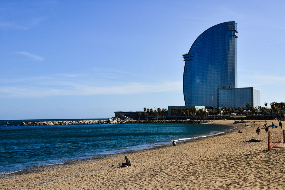 View of Barcelona beach with the iconic W Hotel and clear blue sky.