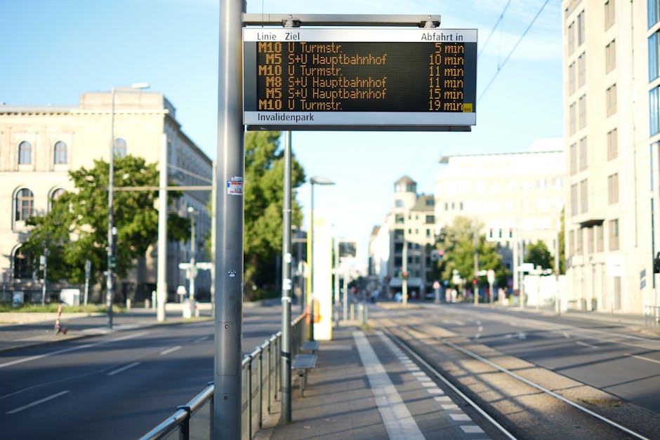 Electronic timetable at a Berlin tram stop with modern urban architecture in the background.