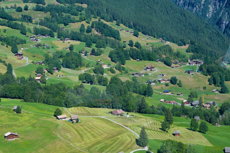 Scenic aerial view of lush green Swiss countryside with scattered villages and farmhouses.