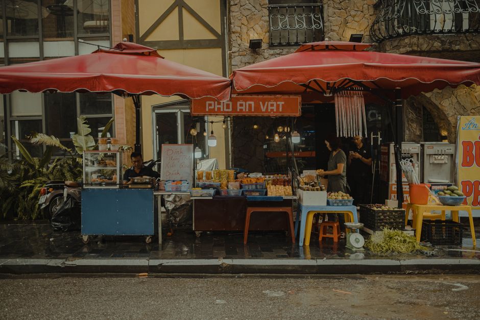 Vibrant outdoor street market featuring local vendors selling fresh produce and goods under red canopies.