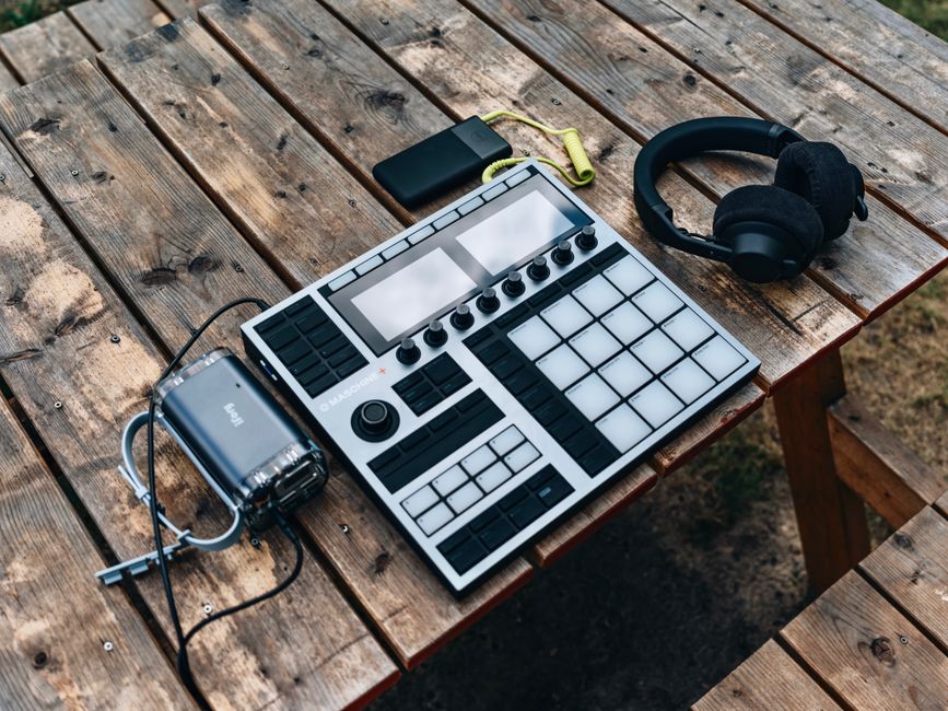 High-angle shot of music production equipment on a wooden table outdoors.