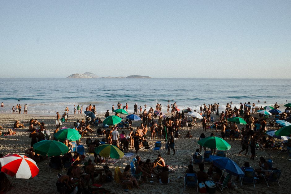 A lively beach scene in Rio de Janeiro with tourists and colorful umbrellas.