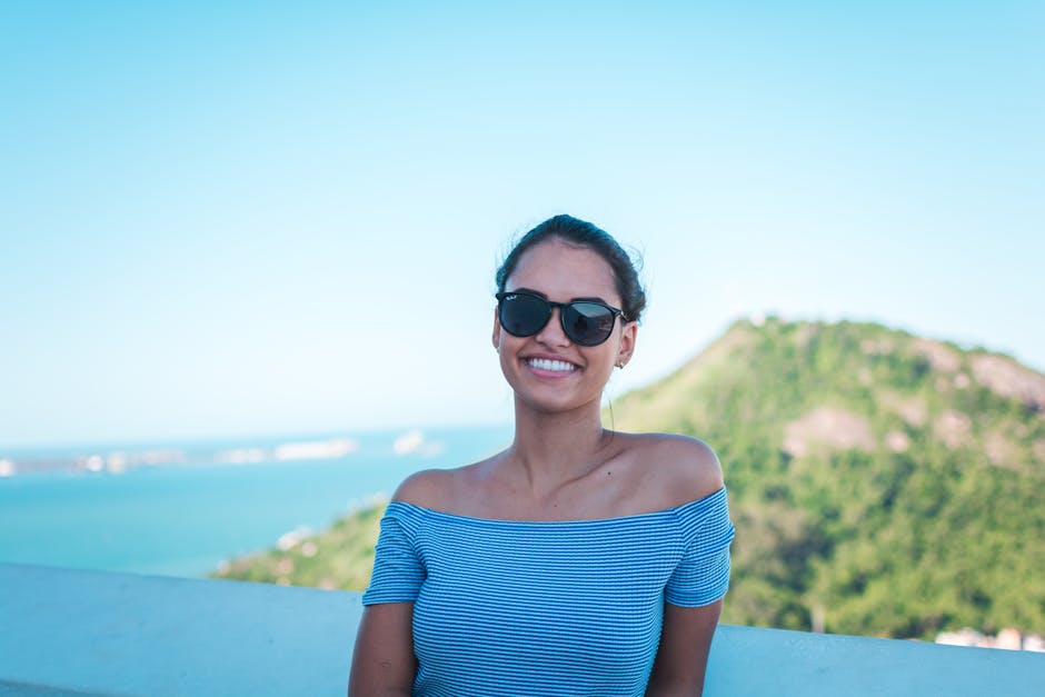 Happy woman in sunglasses enjoying a sunny day outdoors with a beautiful view.