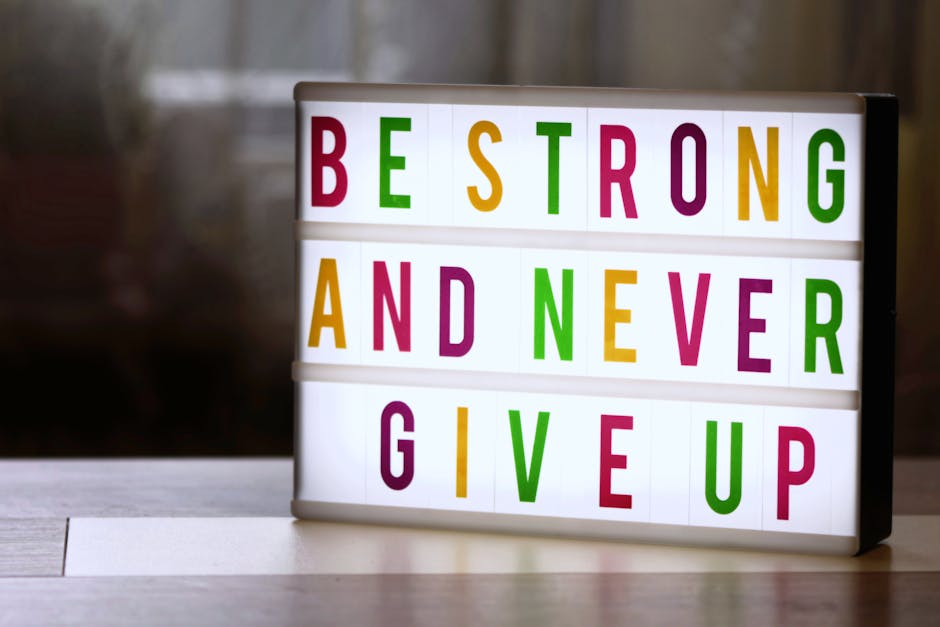 Motivational lightbox sign displaying 'Be Strong and Never Give Up.'